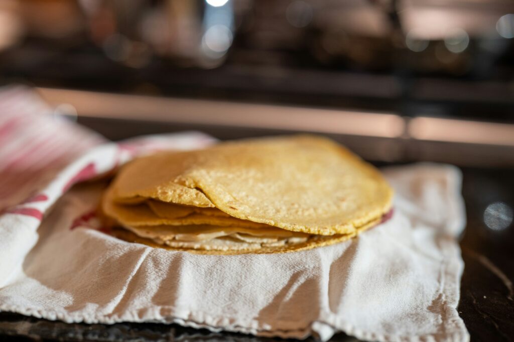 Stack of corn tortillas resting on a folded kitchen cloth
