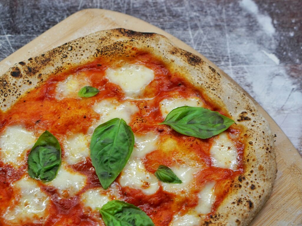 Close-up of a freshly baked Margherita pizza with melted mozzarella, tomato sauce, and basil leaves on a rustic crust.