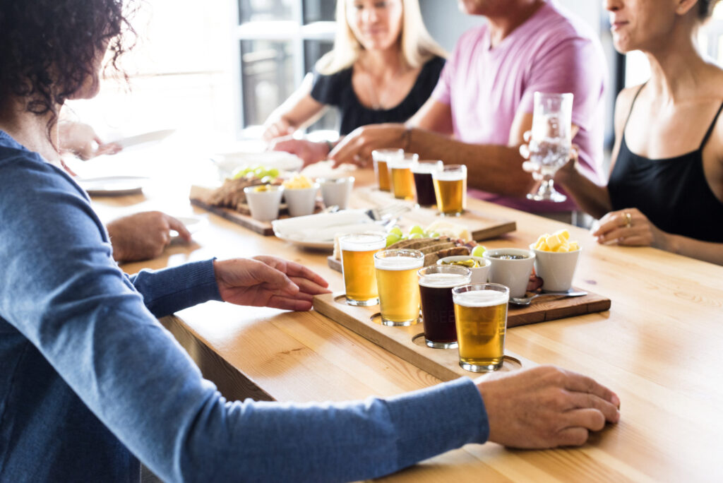 Group of people seated at a table sharing beer flights and small plates in a casual dining setting.