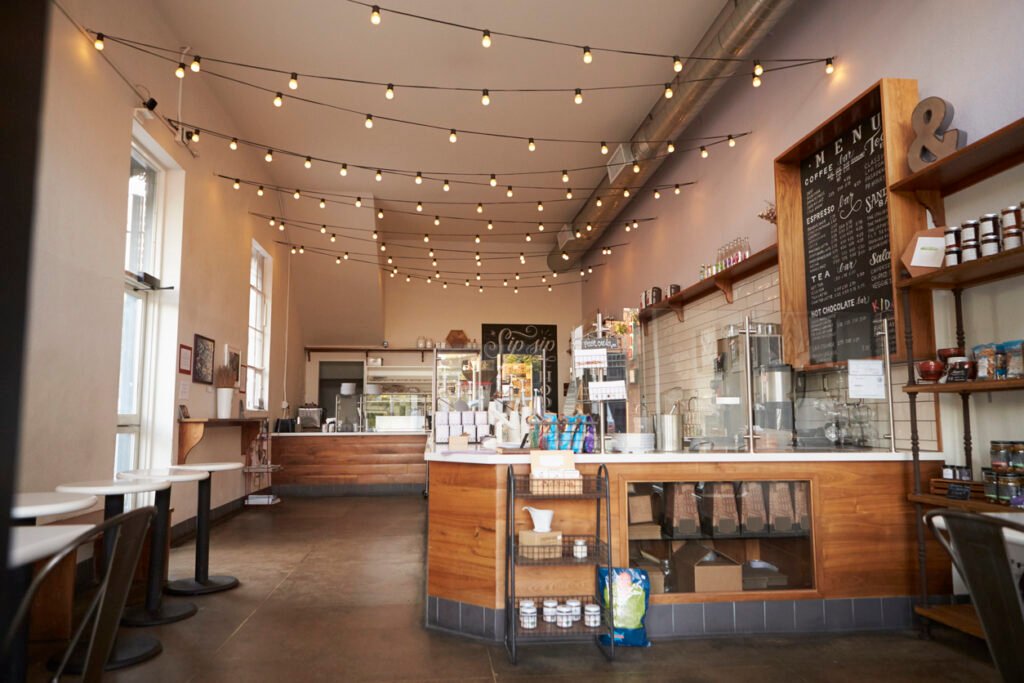 Bright café interior with wooden counter, menu board, and hanging string lights