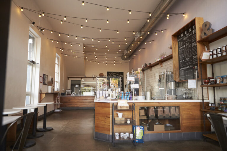 Bright café interior with wooden counter, menu board, and hanging string lights