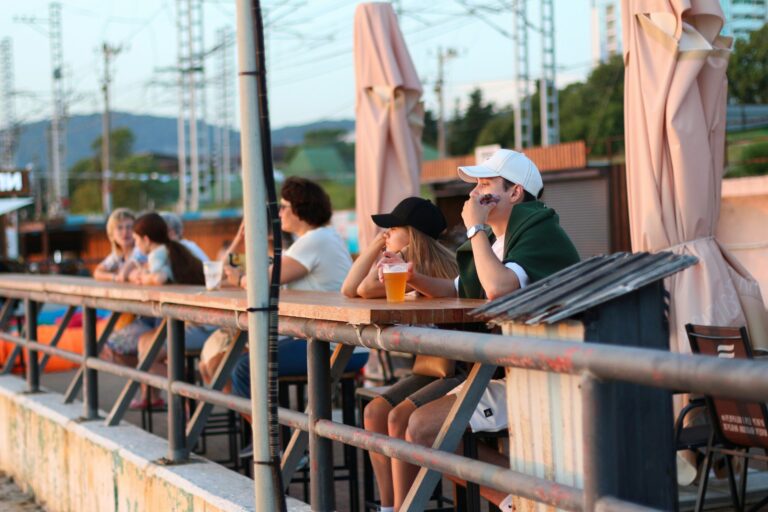 People seated at outdoor tables on a patio with umbrellas