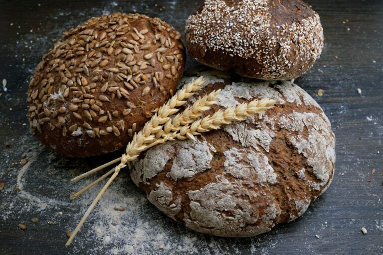 Two rustic round loaves of bread with floured crusts resting on a dark surface.