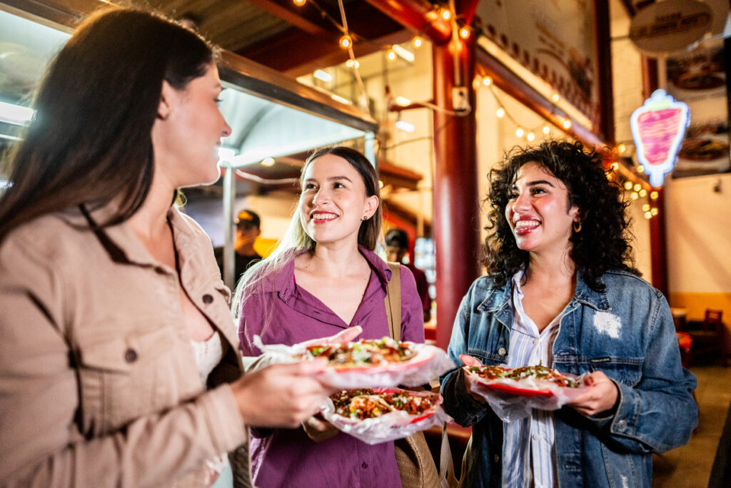 Friends enjoying street tacos together at a lively outdoor food market.