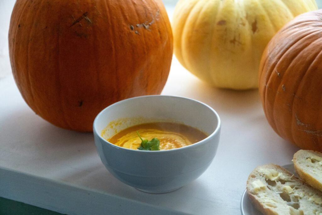 Bowl of soup with pumpkins behind it